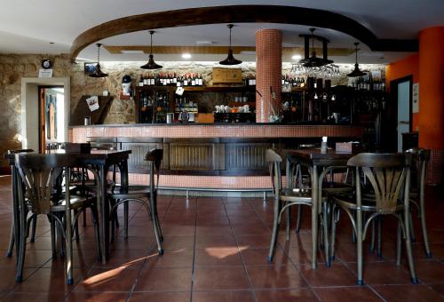 um restaurante com mesas e cadeiras e um bar em Pensión O Prouso em San Mamede de Carnota