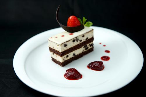 a piece of cake on a white plate with a strawberry on top at Olinia Airport Hotel in Katunayake