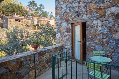 a stone building with a table and chairs on a balcony at Casa Nascente - Água Formosa _ Vila de Rei in Vila de Rei