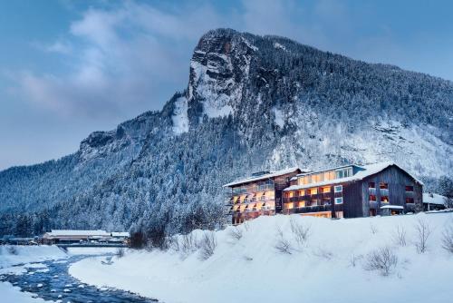 um edifício na neve ao lado de uma montanha em Hotel Krone in Au em Au im Bregenzerwald