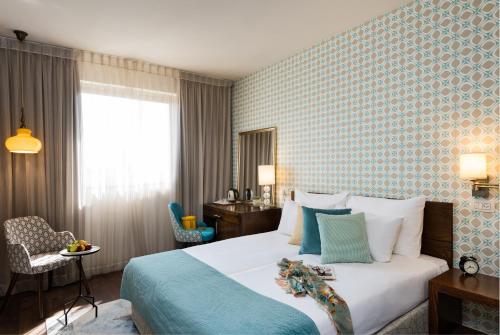 ein Hotelzimmer mit einem Bett, einem Schreibtisch und einem Fenster in der Unterkunft Prima Royale Hotel in Jerusalem
