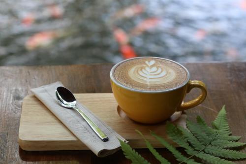 een kopje koffie op een houten tafel met een lepel bij Chayana Resort in Ban Mai Phatthana