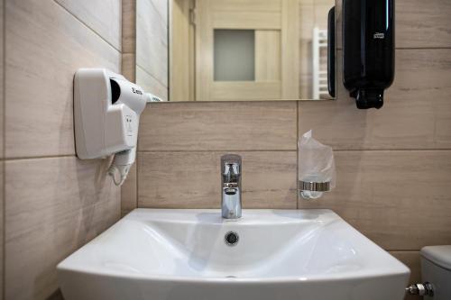 a bathroom sink with a soap dispenser on the wall at Airport House in Otopeni