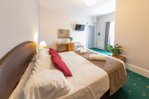 a bedroom with a large bed with red pillows at The Clee Hotel - Cleethorpes, Grimsby, Lincolnshire in Cleethorpes