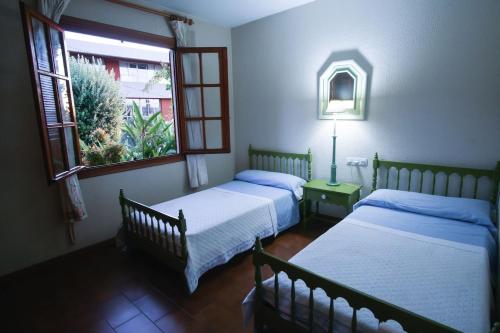 two beds in a room with two windows at Chalet con piscina y 2000 m de jardín in Vigo