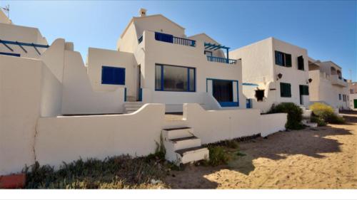 a large white house on the beach next to a building at Playa de Caleta de Famara in Famara