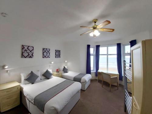 a bedroom with two beds and a ceiling fan at OYO Marina in Sandown