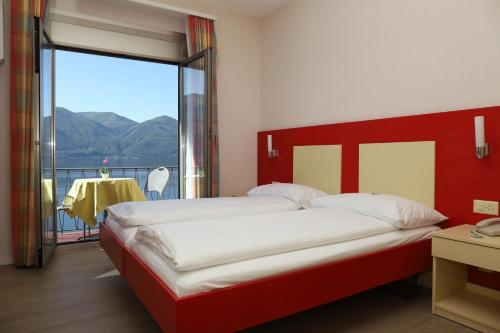 a bedroom with a large bed and a large window at Hotel Arancio in Ascona