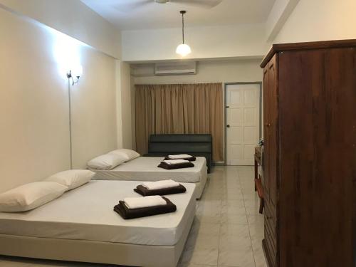a bedroom with two beds and a cabinet with towels at Nusantara Mattwaddien M.S in Kota Kinabalu