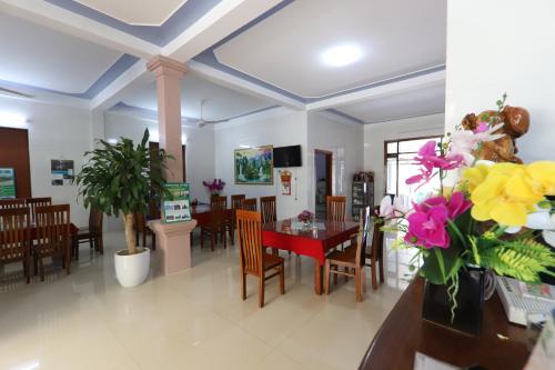 uma sala de jantar com mesa, cadeiras e flores em Son Doong Riverside em Phong Nha