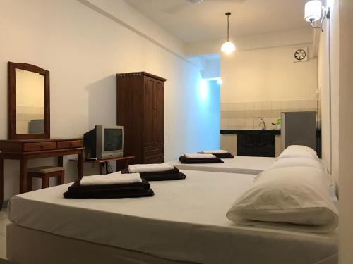 3 Betten in einem Zimmer mit einem TV und einer Küche in der Unterkunft Nusantara Mattwaddien M.S in Kota Kinabalu
