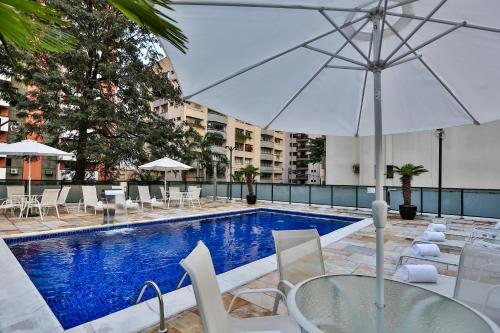 a pool with a table and chairs and an umbrella at Roomo Residencial Itaim Bibi by Transamérica in São Paulo