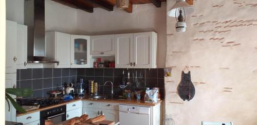 uma cozinha com armários brancos e uma bancada em Maison LINDA Ch. d'hôte em Grateloup