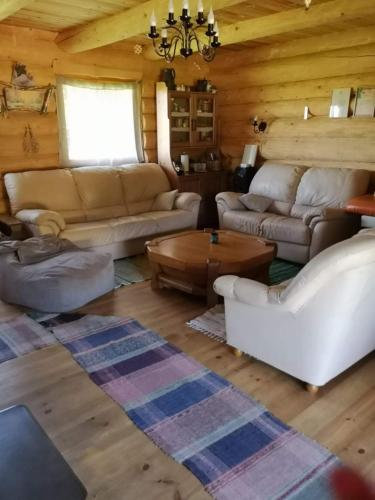 a living room with couches and a table in a cabin at Pirts māja Ramatas in Skulte