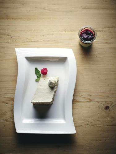 a white plate with a piece of cake and a raspberry at Kinderhotel Stegerhof in Donnersbachwald