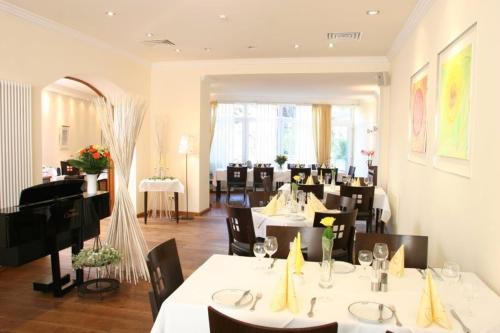 a restaurant with white tables and chairs and a piano at Hotel Restaurant Rothkopf in Euskirchen