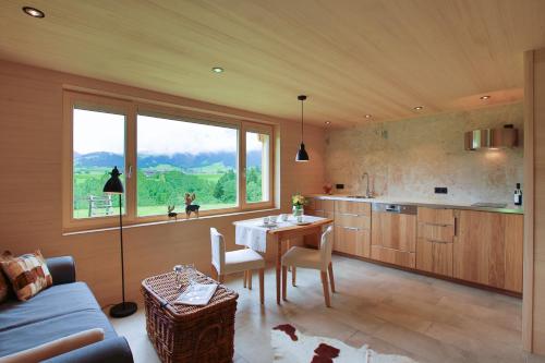 eine Küche und ein Esszimmer mit einem Tisch und einem Fenster in der Unterkunft Gartenstudio Waldblick in Schwarzenberg im Bregenzerwald