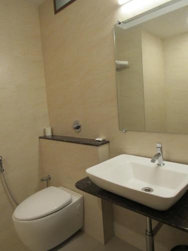 uma casa de banho com um lavatório, um WC e um espelho. em Palguni Residency em Hassan