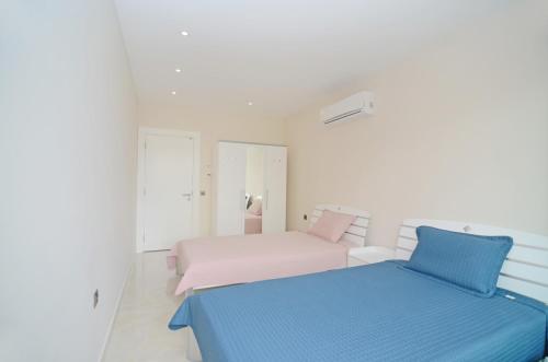 two beds in a white room with blue and pink at Konak Tower sea view apartment 47 in Alanya