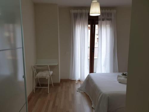 a bedroom with a bed and a table and a window at Apartamento Turistico Puente Romano P3 BAJO - B in Salamanca