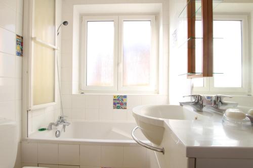 a white bathroom with a tub and a sink at Colmar Nature - Quiet Apartment MARAICHERS in Colmar