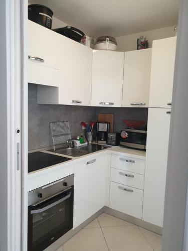 une cuisine blanche avec des armoires blanches et un évier dans l'établissement Cocooning, à Menton
