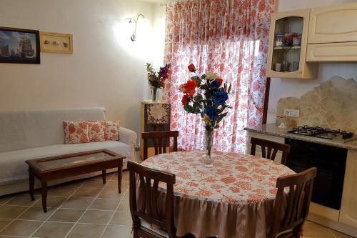 Luxury apartament Alice في أولبيا: غرفة معيشة مع طاولة مع إناء من الزهور عليها