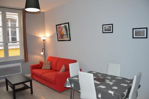 Una sala de estar con un sofá rojo y una mesa. en Logis du Cagaïre, en Le Puy en Velay