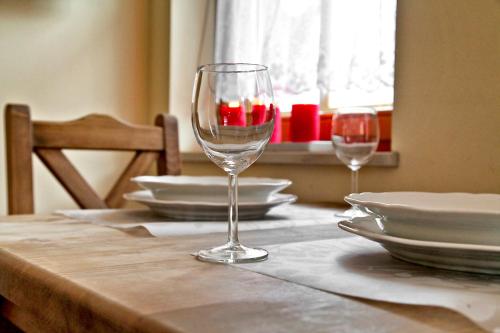 a table with two wine glasses and plates on it at KrokusChata pod Sokolicą in Krościenko