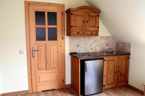 a kitchen with wooden cabinets and a refrigerator and a door at KrokusChata pod Sokolicą in Krościenko