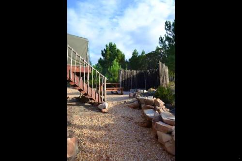 a building with a fence and a wooden staircase at Otium Oasis Glamping & Camping in Hartebeest Rivier