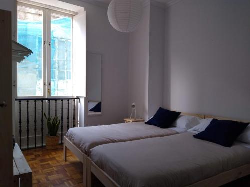 two beds in a room with a window at A casa da Liberdade in Ourense