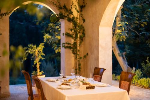 a table with a white table cloth and chairs and an archway at Agroturizem Gjepali in Shijak