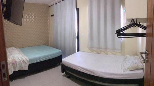 two beds in a small room with a window at Apartamentos da praia in Arraial do Cabo