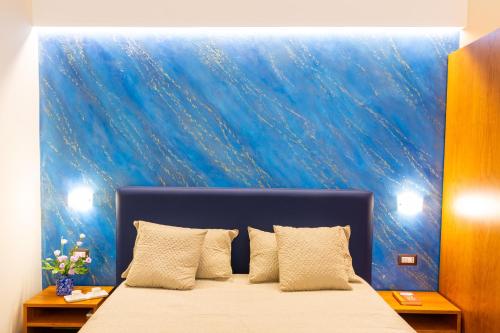 a bedroom with a bed with a blue wall at Il Melograno Relais in Vico Equense