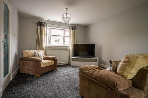 a living room with two chairs and a flat screen tv at Hopetoun House in Springside