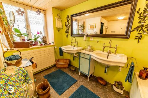 a yellow bathroom with two sinks and a mirror at Pension Chesselberg in Buckten