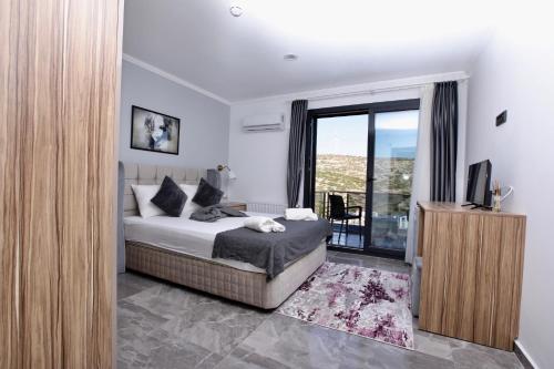 a bedroom with a bed and a television and a balcony at FONTANA HOTEL FENER in Çeşme