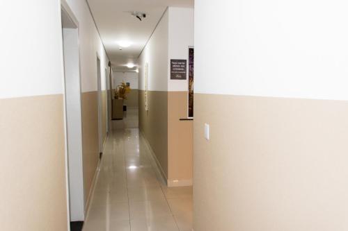 a hallway with white walls and a white tile floor at Pousada Du Valle in Embu