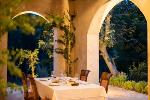 a table with a white table cloth and chairs and an archway at Agroturizem Gjepali in Shijak