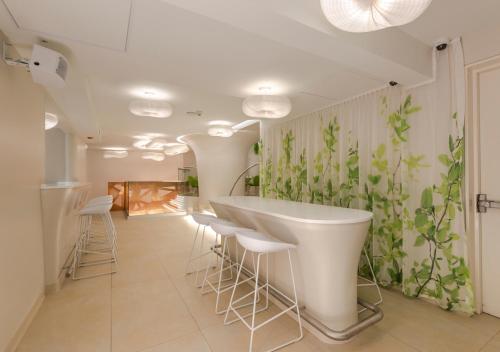 a room with a white bar with stools and plants on the wall at 45 by Director in Santiago