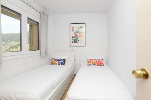 Duas camas brancas num quarto branco com uma janela em Apartamento Fontargent em Soldeu