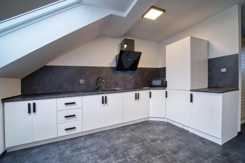 a kitchen with white cabinets and a sink at Národní dům Podbořany in Podbořany