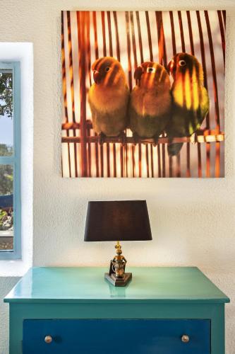 a table with a lamp and a picture of three birds at Riad Tamayourt Ocean View & piscine chauffée à 30 in Essaouira
