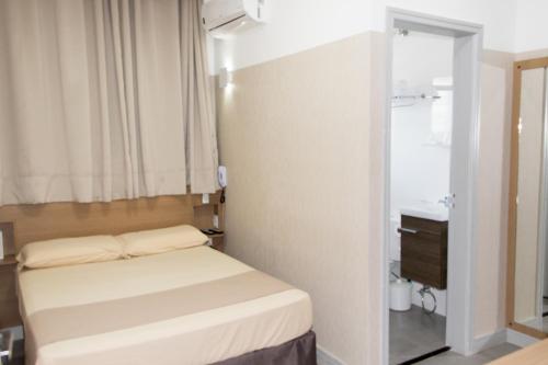 a small bedroom with a bed and a sink at Pousada Du Valle in Embu