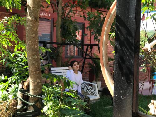 a woman sitting on a bench in a garden at Vu's Homestay in Phong Nha