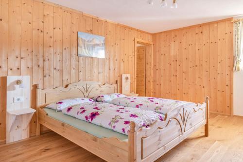 1 dormitorio con 1 cama en una pared de madera en Tielerhof, en Aldino