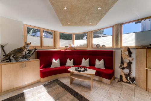 a living room with a red couch and some windows at Apart Garni Hax'n Tenne in Serfaus