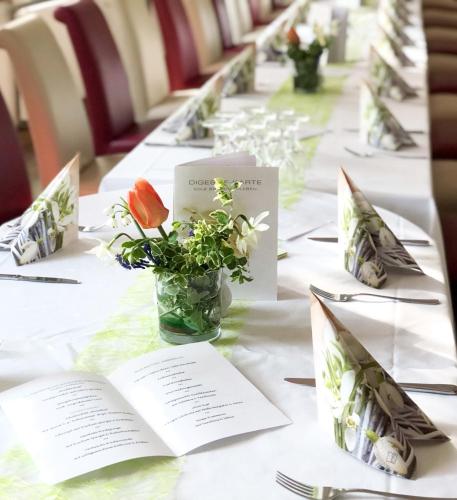 a long table with flowers in a vase on it at Traditionsgasthaus Goldener Löwe Riesa Restaurant & Pension in Riesa
