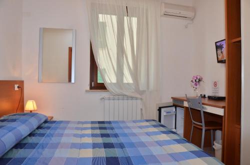 a bedroom with a bed and a desk and a window at Domo - Guest-House Il Nespolo Fiorito in Orosei